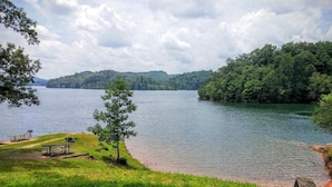 A lakeside view with picnic tables and a wooden deck. - 🪵 Murphy Cabin 🏔 Mountain View // 2Bed-2Bath // 6 guests // 10mins to town (Murphy)