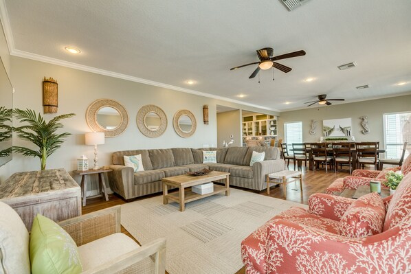 A spacious living room with a large sofa, a coffee table, and a dining area with a table and chairs.