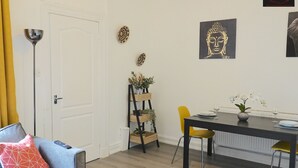 A dining area with a table set for two, a yellow chair, and a black table. There is a white door and a yellow curtain in the background. - One Bedroom Apartment by Klass Living Serviced Accommodation Bellshill - Mossend  Apartment with WIFI  and Parking (Bellshill)