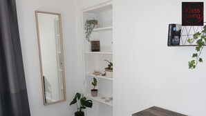 A small, neatly organized room with a wooden table, a mirror, and shelves with plants and decorative items. - One Bedroom Apartment by Klass Living Serviced Accommodation Bellshill - Mossend  Apartment with WIFI  and Parking (Bellshill)