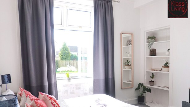 A bedroom with a bed, a bedside table, a lamp, a mirror, and a shelf with plants. - One Bedroom Apartment by Klass Living Serviced Accommodation Bellshill - Mossend  Apartment with WIFI  and Parking (Bellshill)