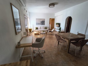 Un espacio habitable moderno con comedor, sofá, televisor y un amplio ventanal.