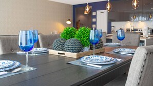 A dining area with a long table set for four, featuring blue glassware, plates, and a centerpiece of pineapples and greenery. - Amazing Townhome Near Disney 42 (Kissimmee)