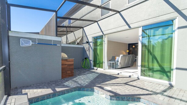 An outdoor swimming pool with a hot tub, a covered patio area, and a view of the interior living space. - Amazing Townhome Near Disney 42 (Kissimmee)