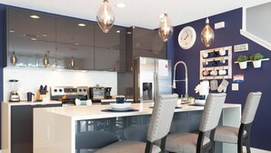 A modern kitchen with dark cabinets, a central island, and bar stools. - Amazing Townhome Near Disney 42 (Kissimmee)