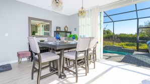 A dining area with a table and chairs, a mirror, and a view of a swimming pool. - Amazing Townhome Near Disney 42 (Kissimmee)