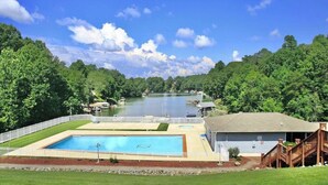 Ein Schwimmbecken mit einer Holzterrasse und Blick auf einen Fluss.