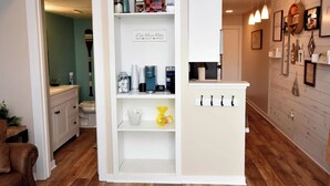 Eine moderne Küche mit weißen Schränken, einer Kaffeemaschine und einer Ablage für Küchenutensilien.