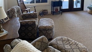 A living room with patterned furniture, a clock on the wall, and a view through a window. - Beautiful Reelfoot Lake (Tiptonville)