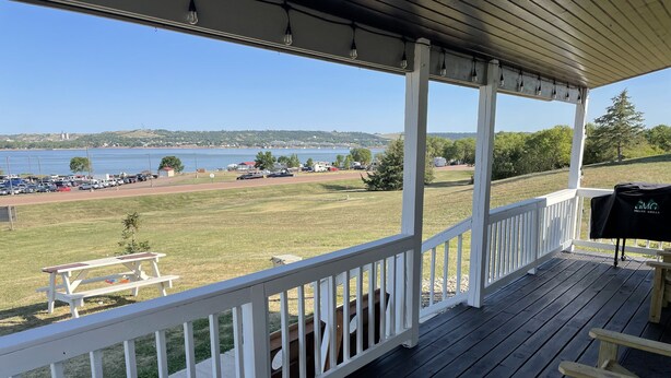 Eine überdachte Terrasse mit Blick auf einen See und einen Parkplatz.