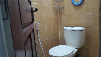A bathroom with a toilet, a shower, and a mirror.