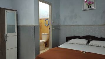 A room with a bed, a wardrobe, and a bathroom visible through an open door.