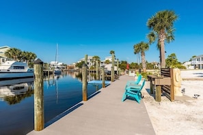 A marina with boats docked, a wooden walkway, and a row of palm trees.