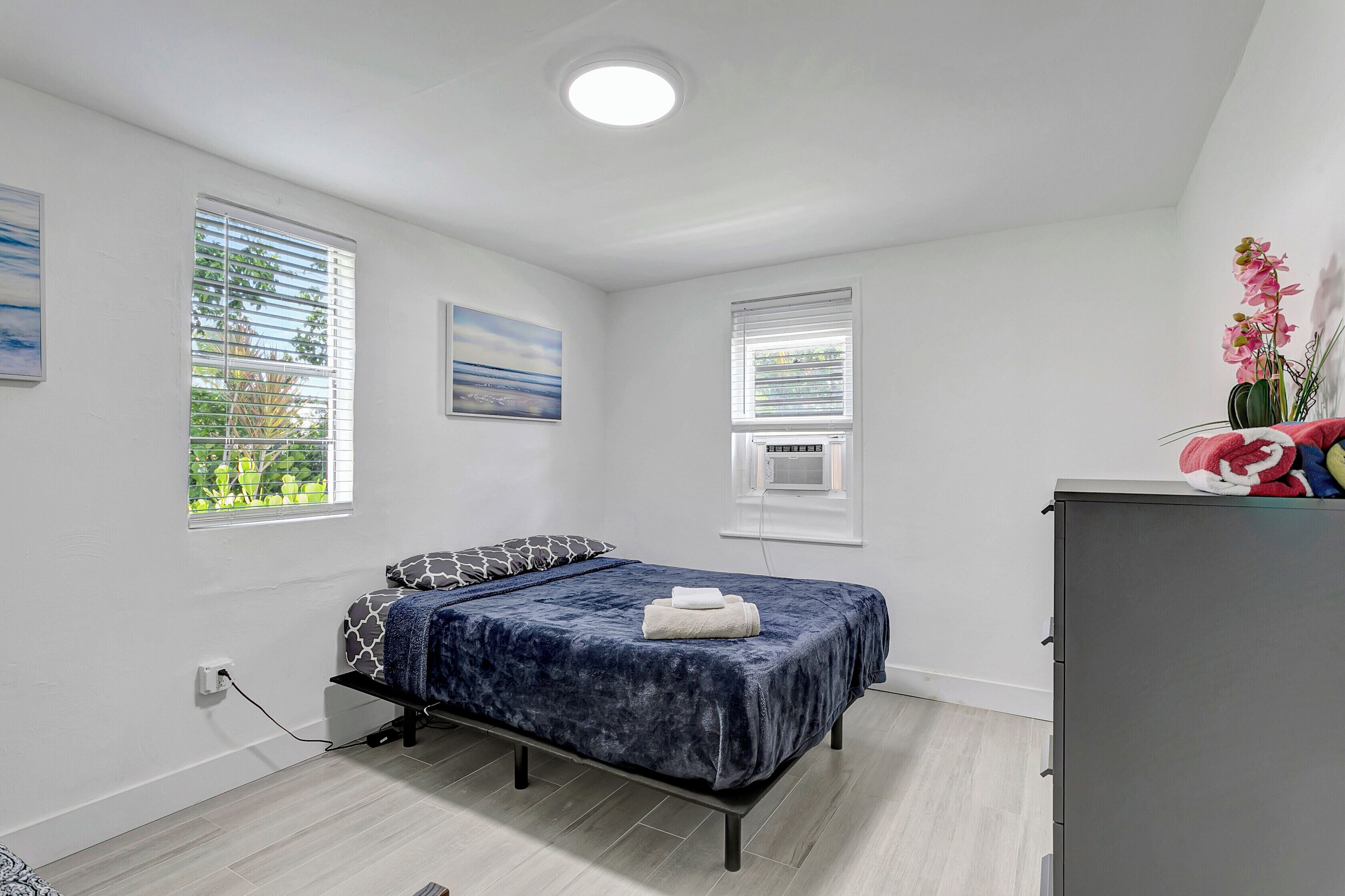 A bedroom with a bed, a desk, and a window with blinds.