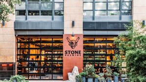 En bygning med et stort skilt, der siger "STONE BREWING", og en glasfacade.