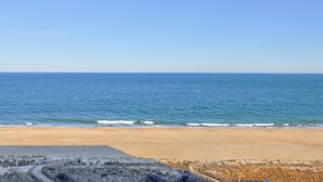 Une plage avec un ciel dégagé, une rive sablonneuse et une zone délimitée par une clôture.