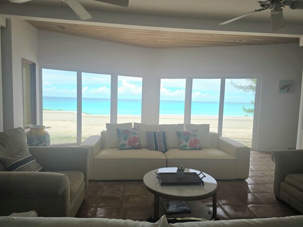 A living room with a sofa, a coffee table, and a view of the beach.