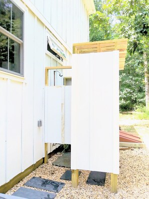 A white building with a window, a door, and a wooden structure.