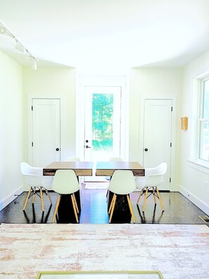 A dining area with a table and chairs, a door with a view, and a window.