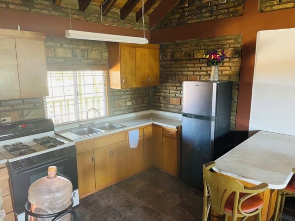 Cocina compacta con estufa a gas, lavamanos y refrigerador.