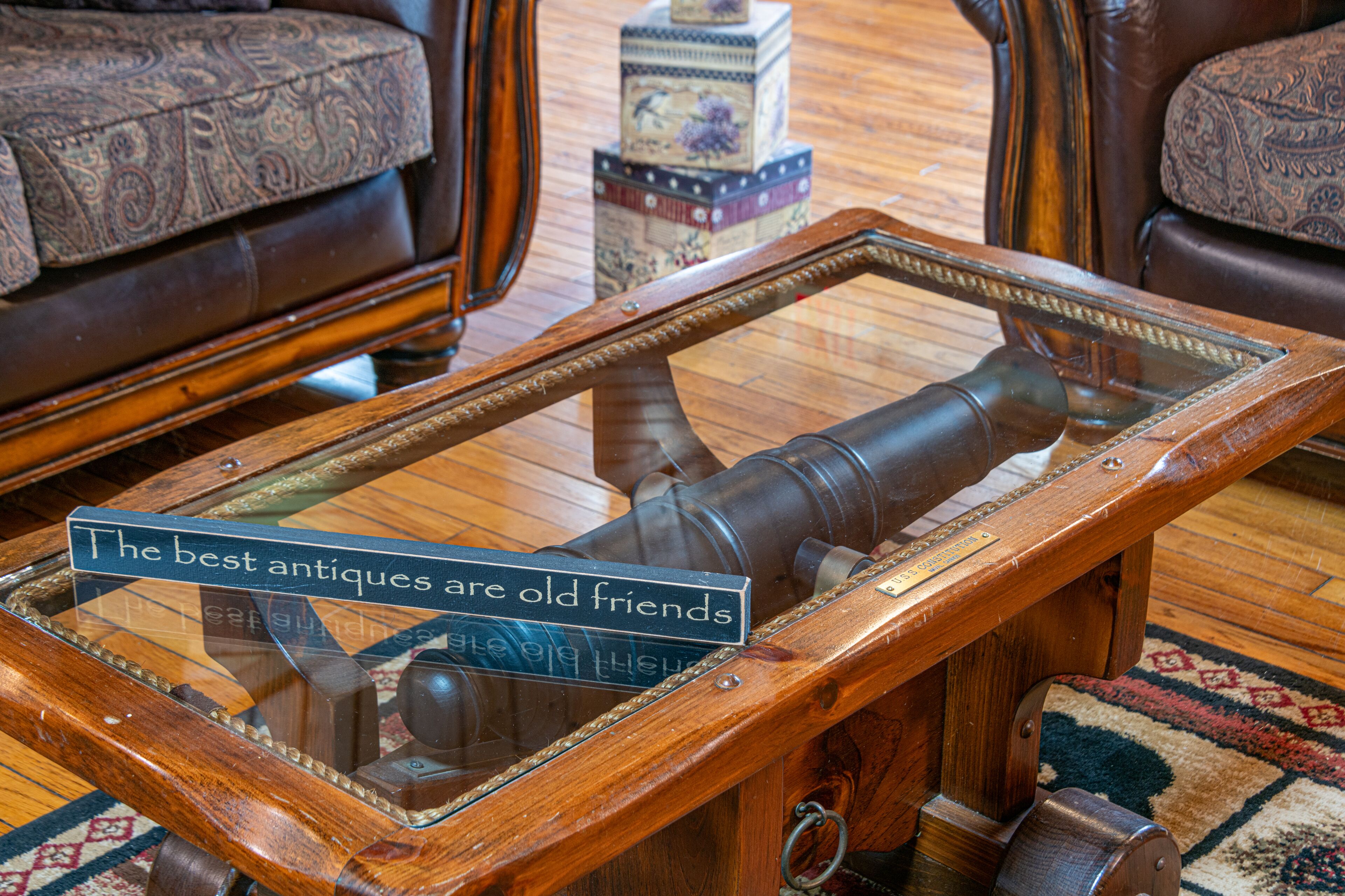 A wooden table with a glass top and a sign that reads "The best antiques are old friends."