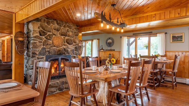 Un coin repas rustique avec une cheminée en pierre, des chaises en bois et une table en bois.