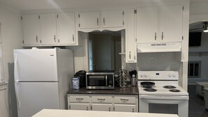 Une cuisine moderne avec des meubles blancs, un réfrigérateur, un four à micro-ondes et une cuisinière.