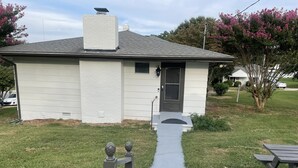 Une maison de plain-pied avec un porche à l’avant, une petite fenêtre et une porte.