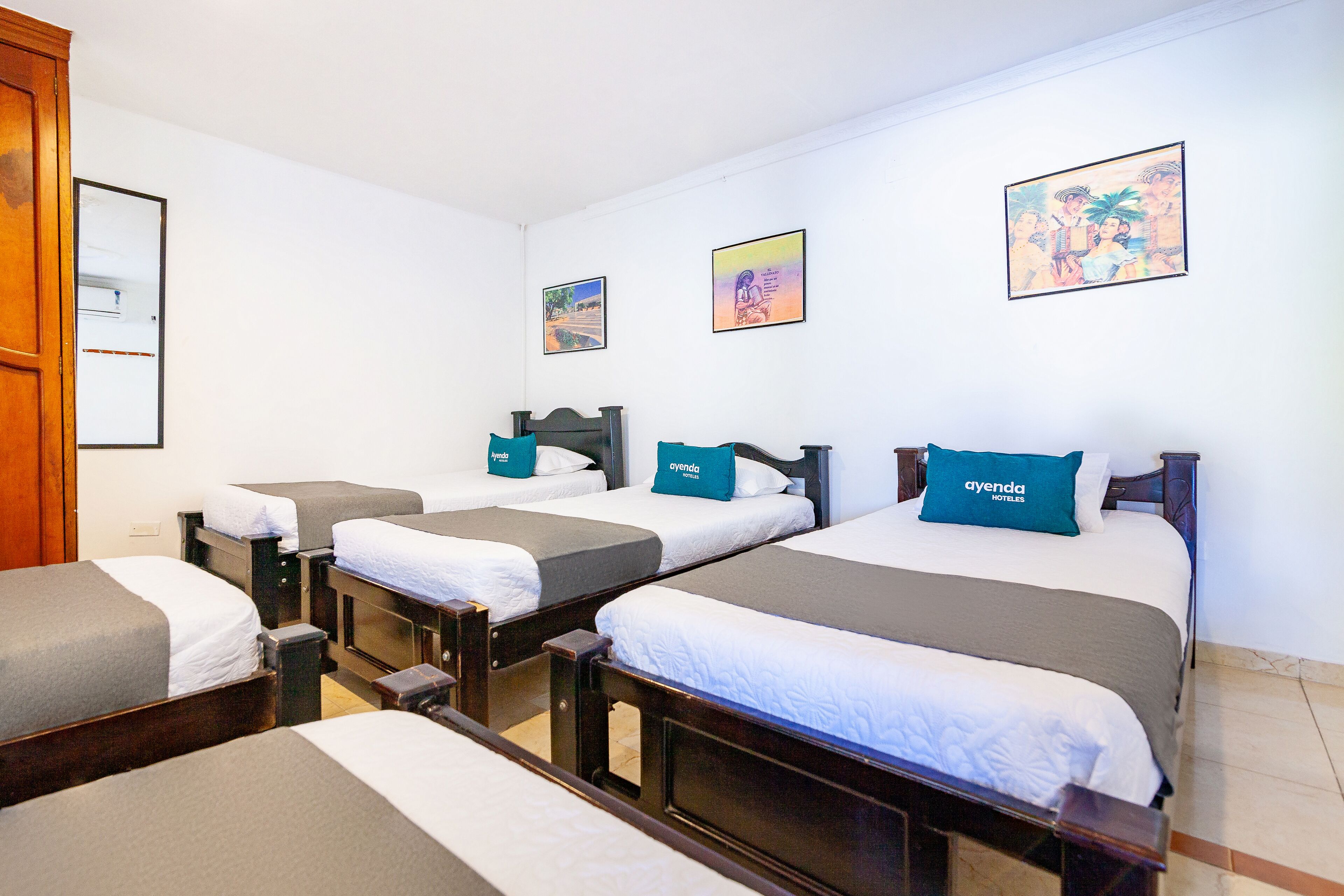 Habitación de hotel con tres camas individuales, cada una con una almohada y una manta.