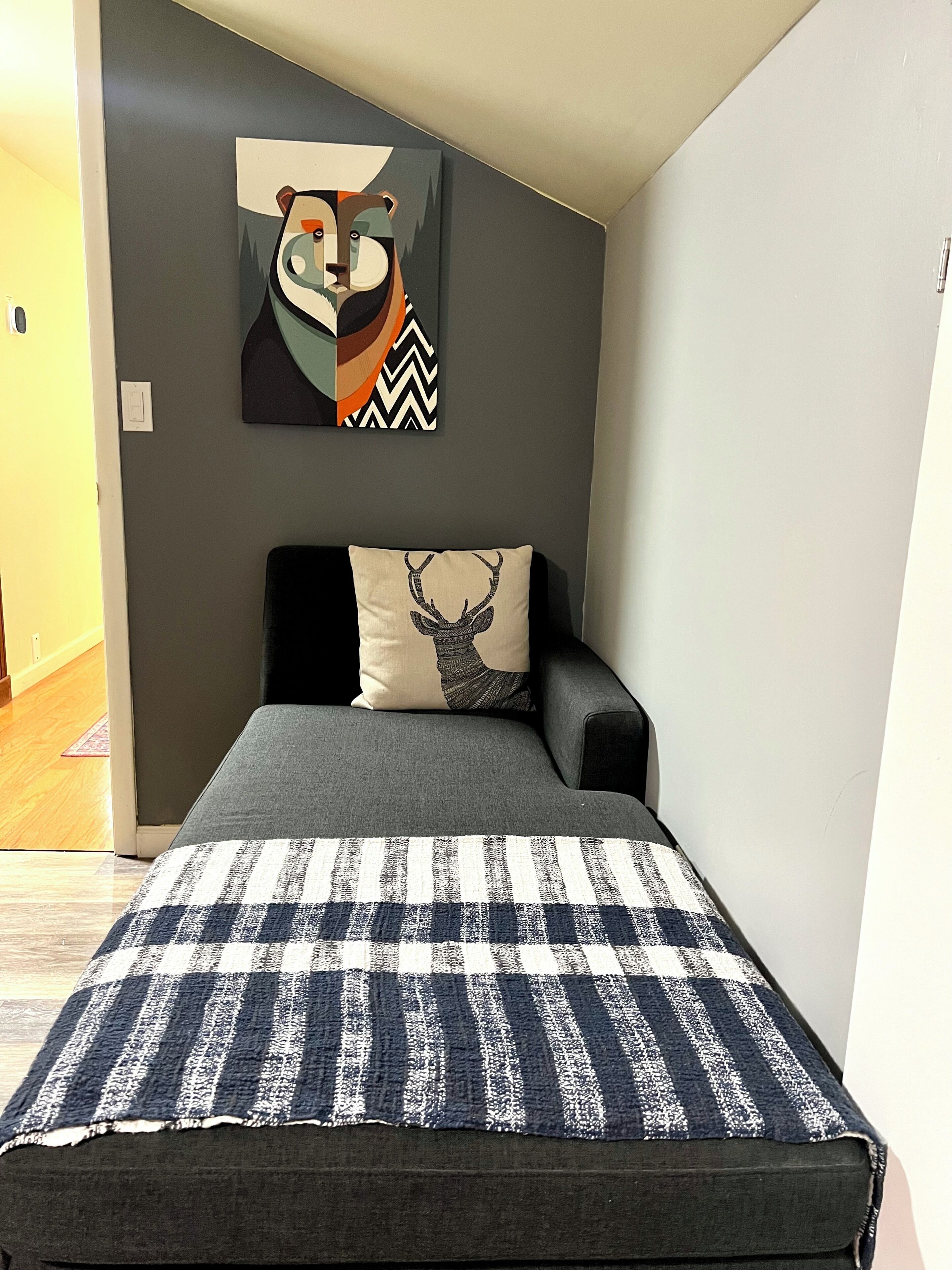 Une chambre à coucher avec un lit, un oreiller orné d’un motif de cerf et une décoration murale représentant un raton laveur.