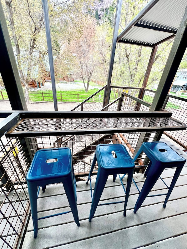 A balcony with metal railings and three blue plastic stools.