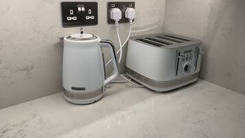 Una cocina con cafetera y tostadora sobre una encimera de mármol.