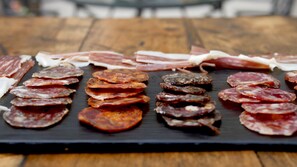 Varietà di salumi esposti su un tagliere di ardesia nera.