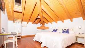 A bedroom with a wooden ceiling, a bed with white bedding, a desk with a laptop, and a chair. - Hotel Branka (Mundaka)