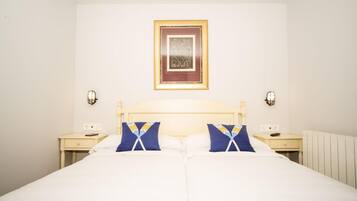 A double bed with two pillows, a nightstand with a lamp, and a framed picture on the wall.