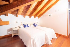 A bedroom with a wooden ceiling, a bed with white bedding, and a nightstand with a lamp. - Hotel Branka (Mundaka)