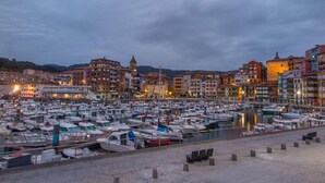 A marina filled with boats, surrounded by historic buildings with a prominent tower. - Hotel Branka (Mundaka)