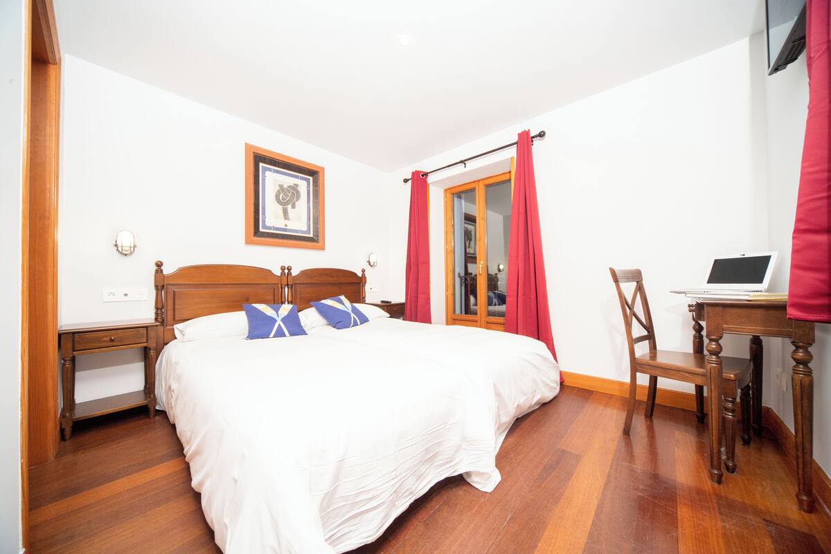 Un dormitorio con una cama de madera, un escritorio con una computadora portátil y una silla.