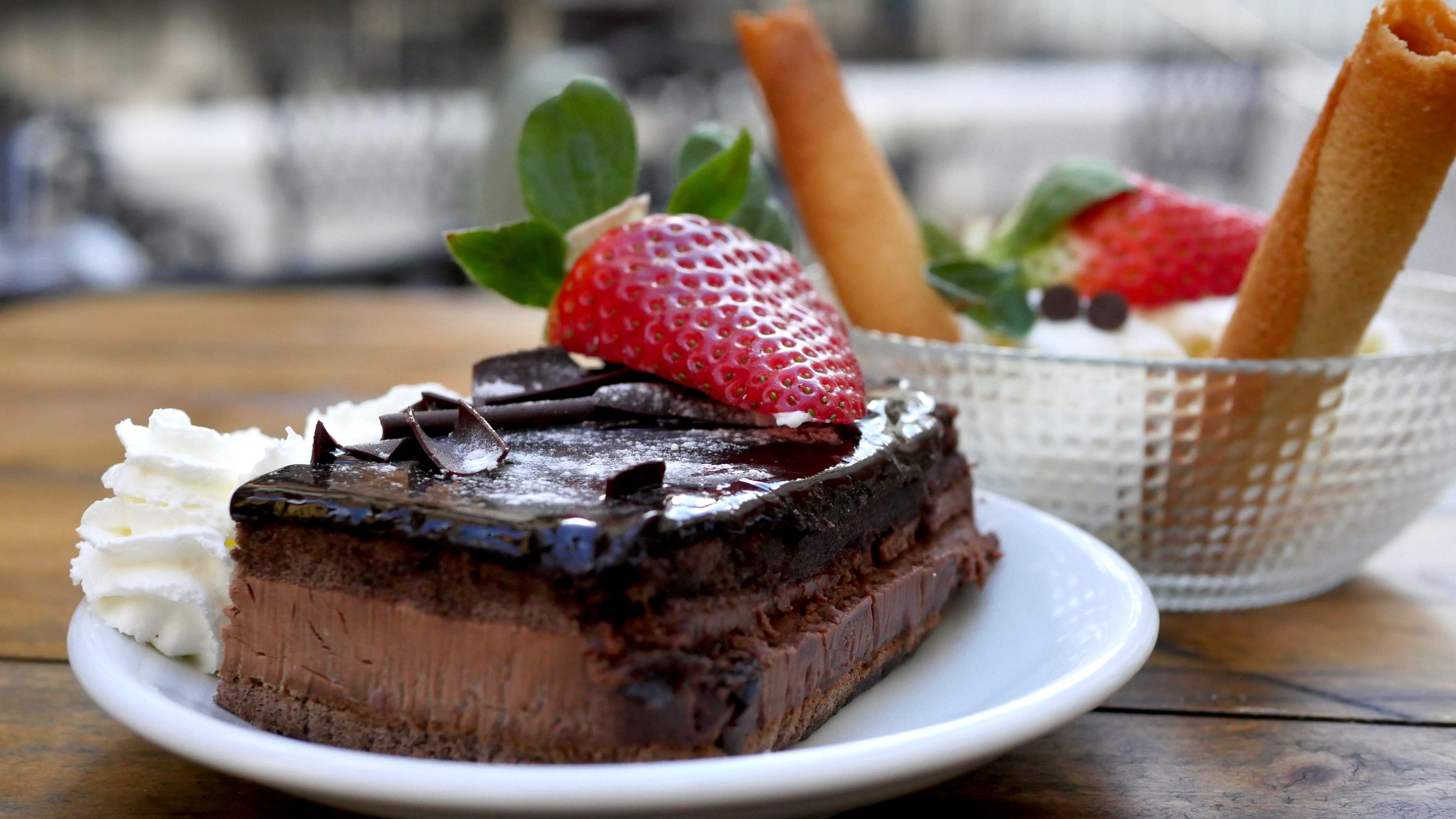 Una porción de pastel de chocolate con crema batida y fresas sobre un plato.