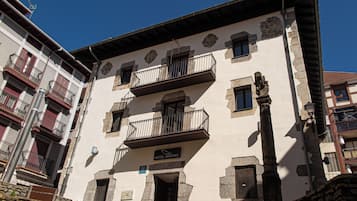 Un edificio de varios pisos con balcones, un cartel que indica que es un hotel y detalles arquitectónicos de piedra.