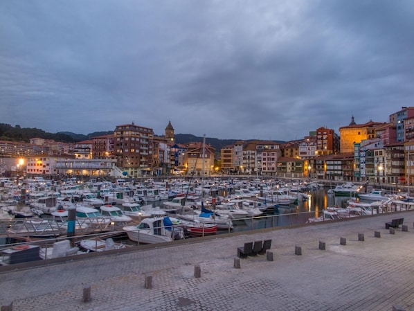 Una marina piena di barche, circondata da edifici storici con una torre imponente.