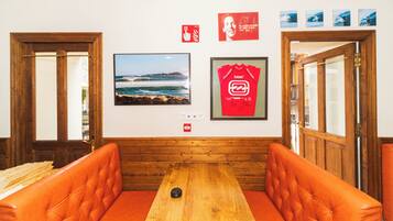 A room with a wooden bench, a framed surfboard, and a framed photograph of a surfer.
