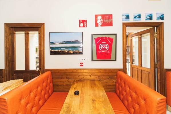 A room with a wooden bench, a framed surfboard, and a framed photograph of a surfer. - Hotel Branka (Mundaka)