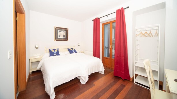 A bedroom with a bed, a nightstand, a wardrobe, and a door. - Hotel Branka (Mundaka)