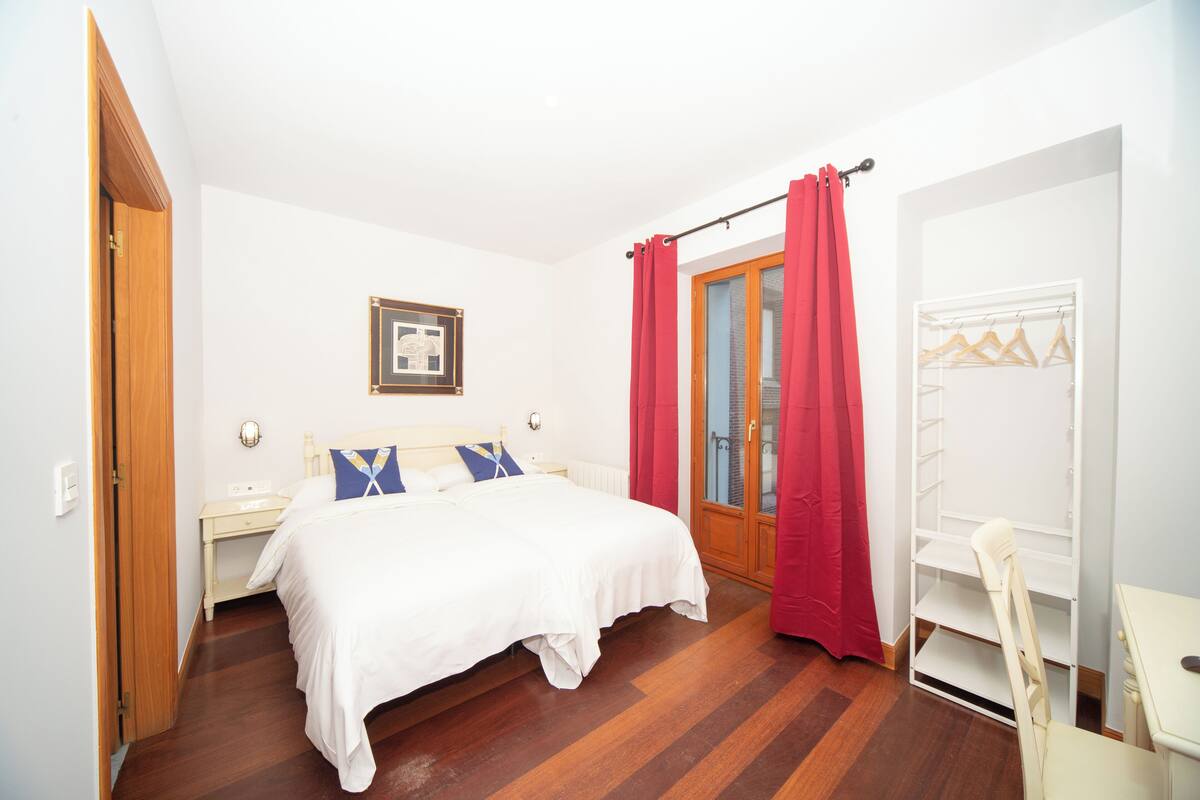 Un dormitorio con cama, mesita de noche, armario y una silla.