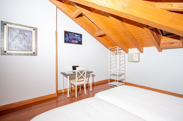 A bedroom with a sloped ceiling, a bed, a desk with a chair, a wall-mounted TV, and a framed picture. - Hotel Branka (Mundaka)