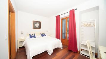 Un dormitorio con cama, mesita de noche, silla, armario y puerta.