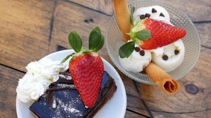 A dessert plate with chocolate cake, whipped cream, strawberries, and chocolate chips. - Hotel Branka (Mundaka)