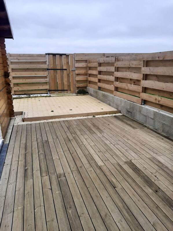 A wooden deck with a concrete border and a wooden fence. - The Quiberville Hut (Quiberville)
