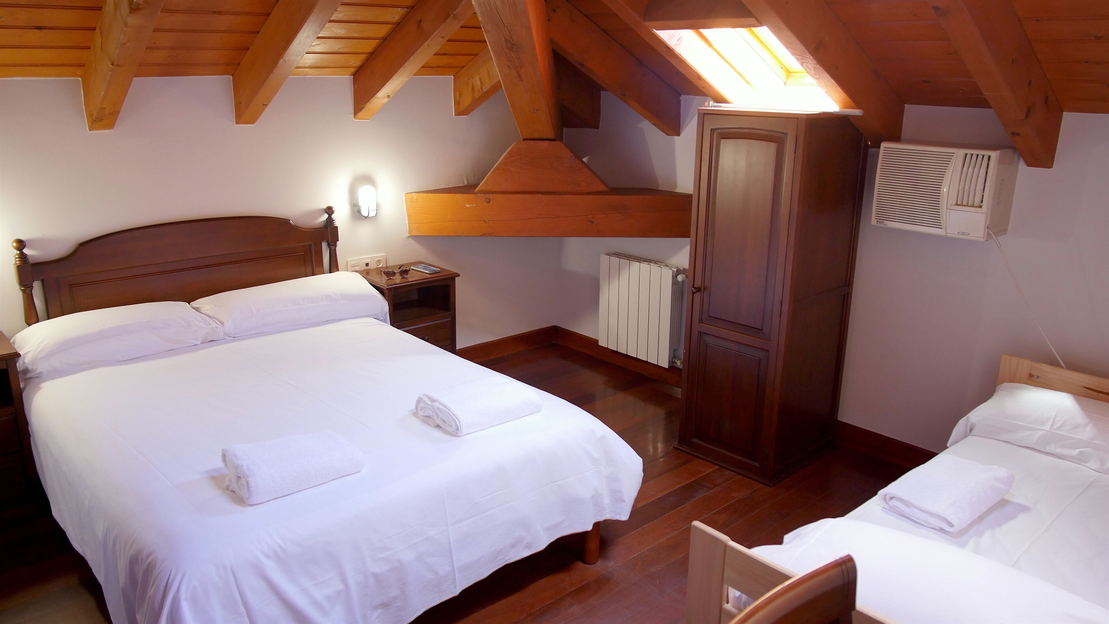Un dormitorio con una cama grande, un armario de madera, una mesita de noche y un radiador.